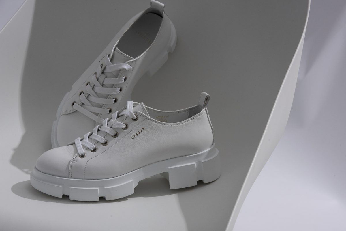 Zwei weisse Leder-Sneaker mit Plateausohle auf gebogenem weissem Untergrund — Das Studiozwei, Werbefotograf München