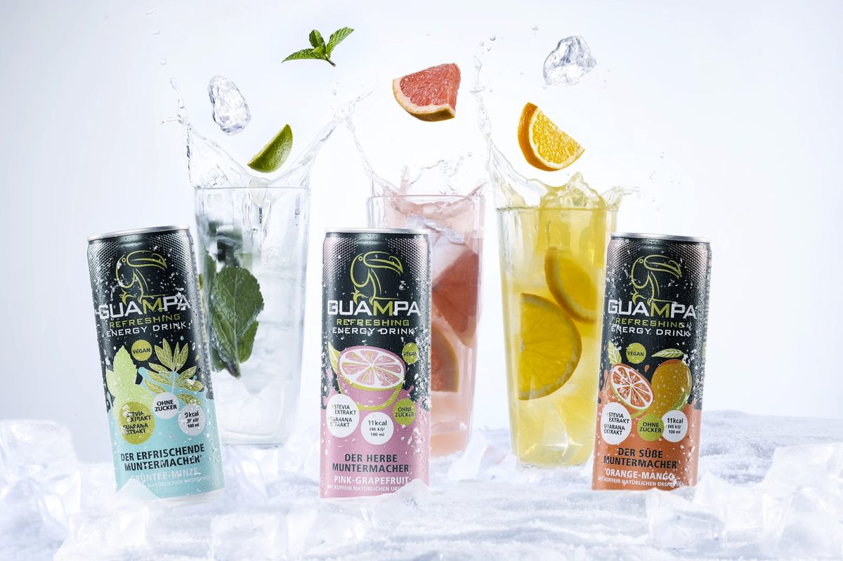 Drei Guampa Energy Drink Dosen vor Glaesern mit Eis, Fruechten und Wasserspritzern — Das Studiozwei, Werbefotograf München
