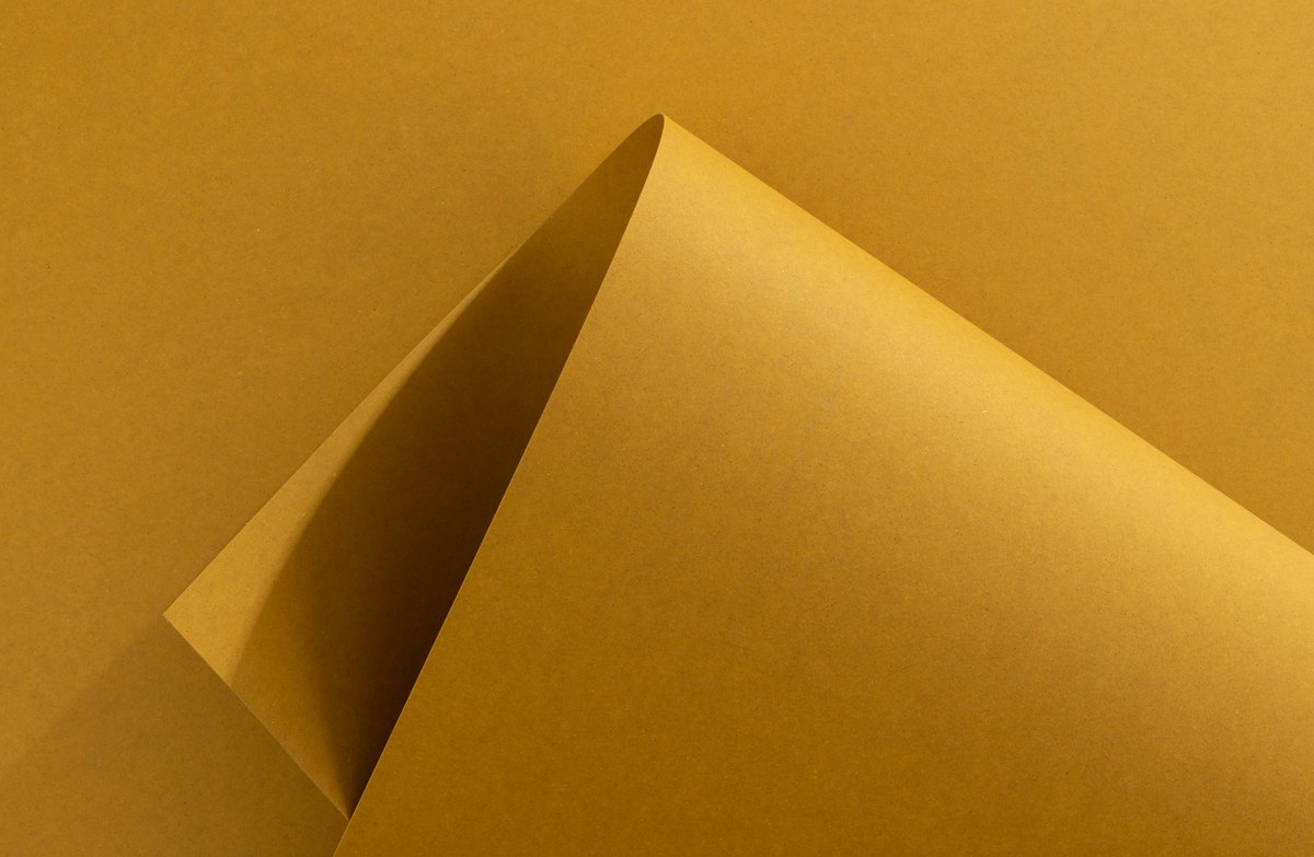 Gelber Papierbogen mit spitz eingerollter Ecke und Schlagschatten im Inneren — Das Studiozwei, Werbefotograf München